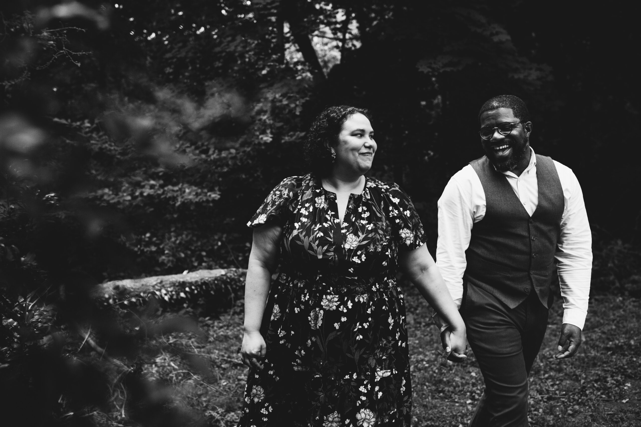 The happy couple walks together hand in hand through a natural setting outside