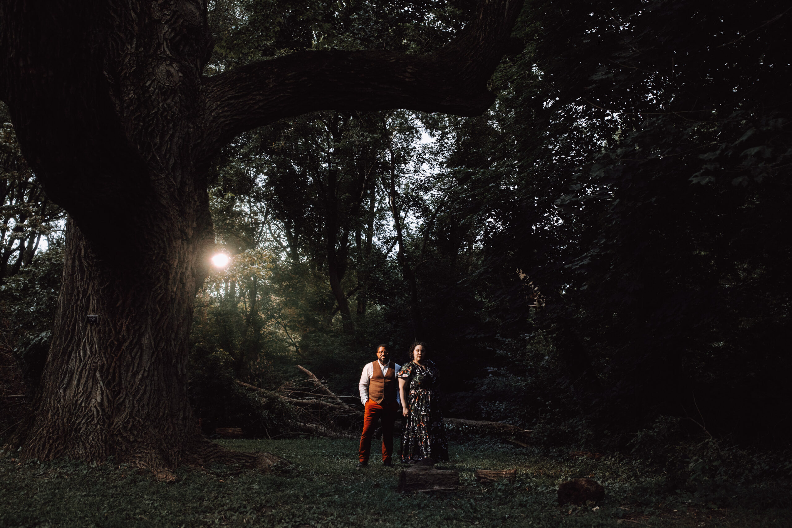 Cayla and Windsor pose together under the branch of a large tree as the sky grows dark