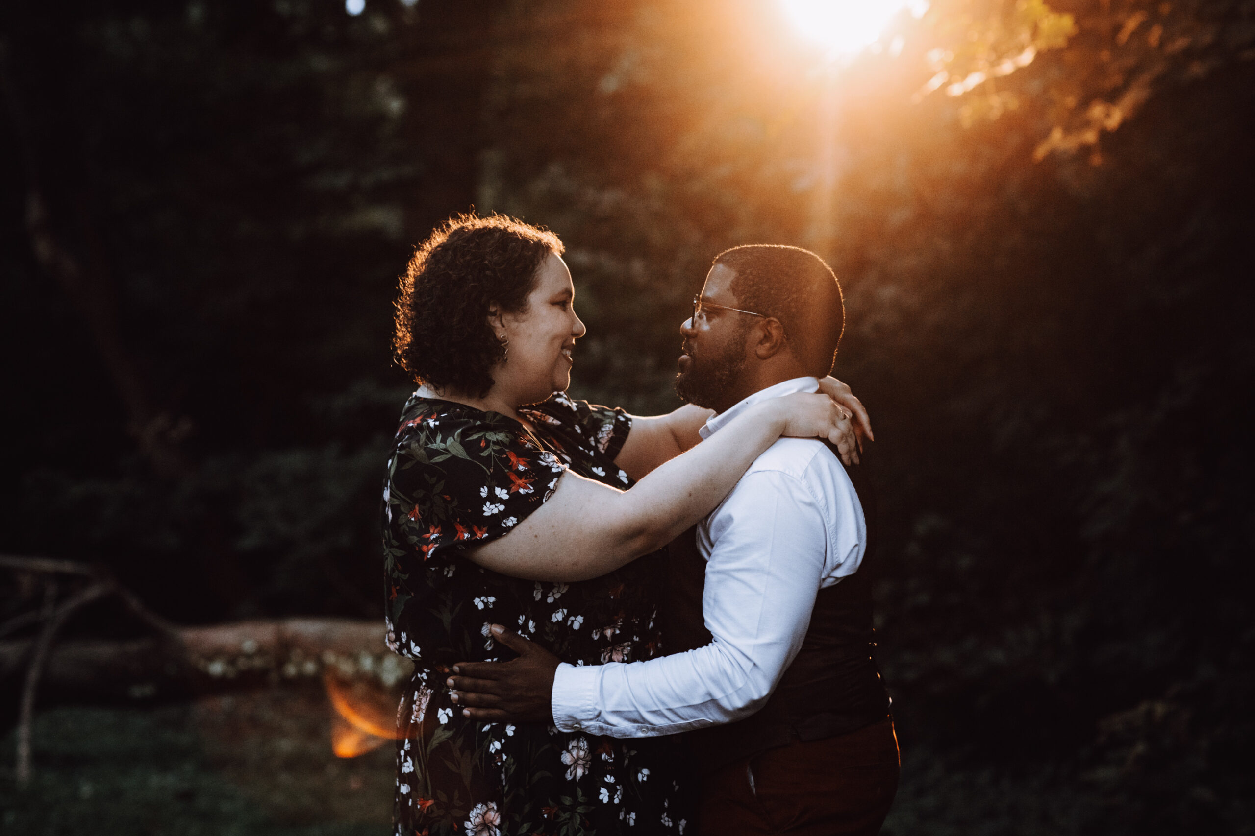 Cayla and Windsor face each other and embrace as they are lit up by beautiful glowing sunset light during their couple portrait session